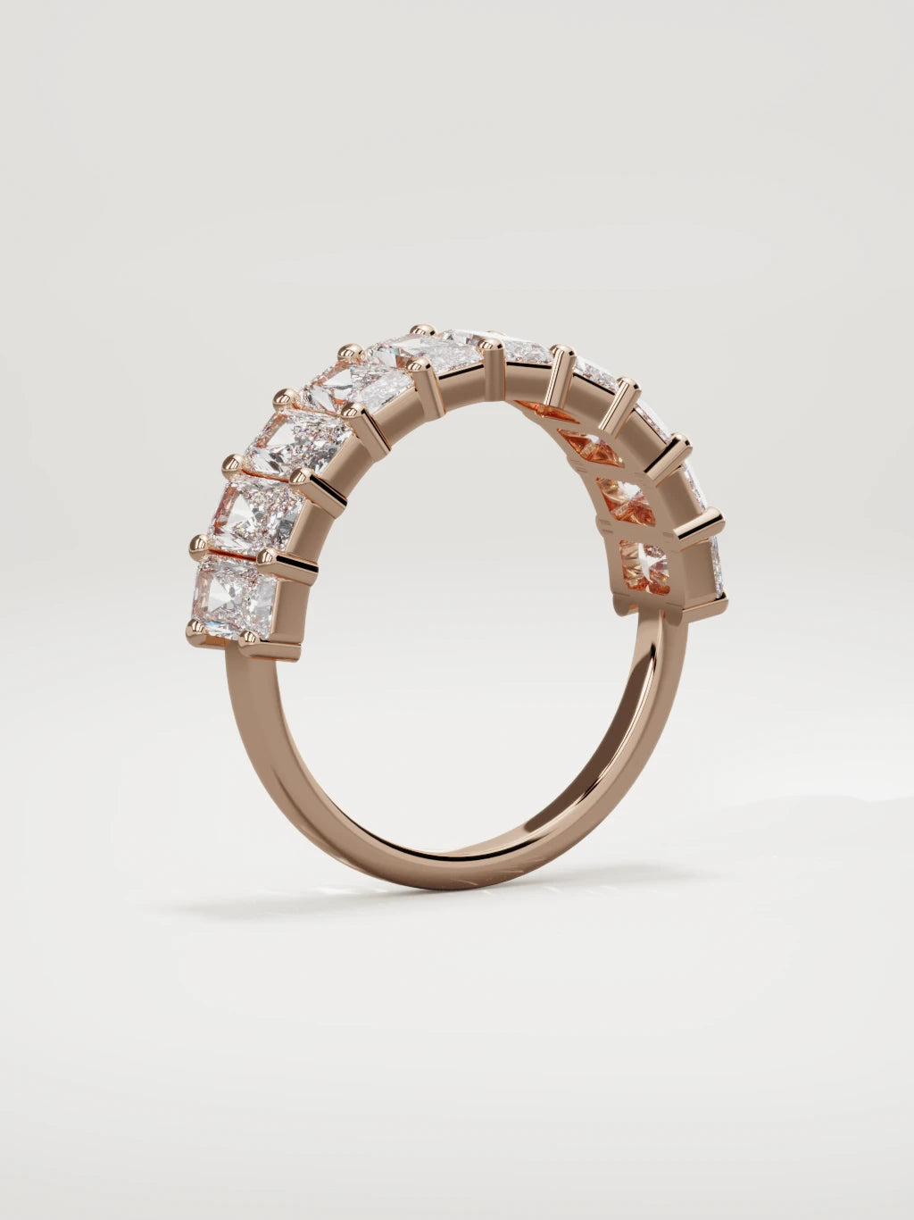 The Astra large prong radiant-cut half eternity band in 14K rose gold, standing three-quarter view