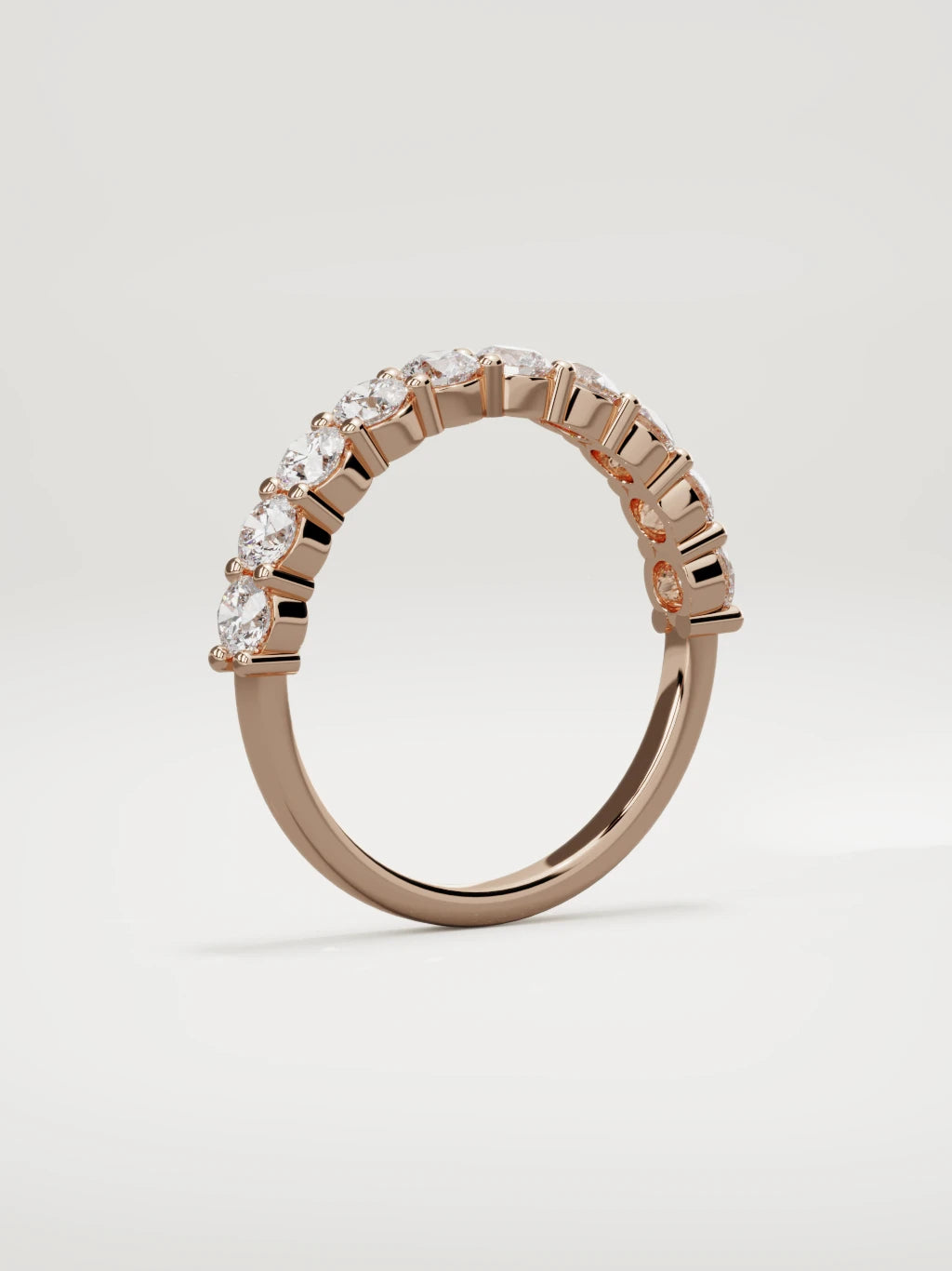 The Clara shared-prong half eternity band in 14K rose gold, standing three-quarter view
