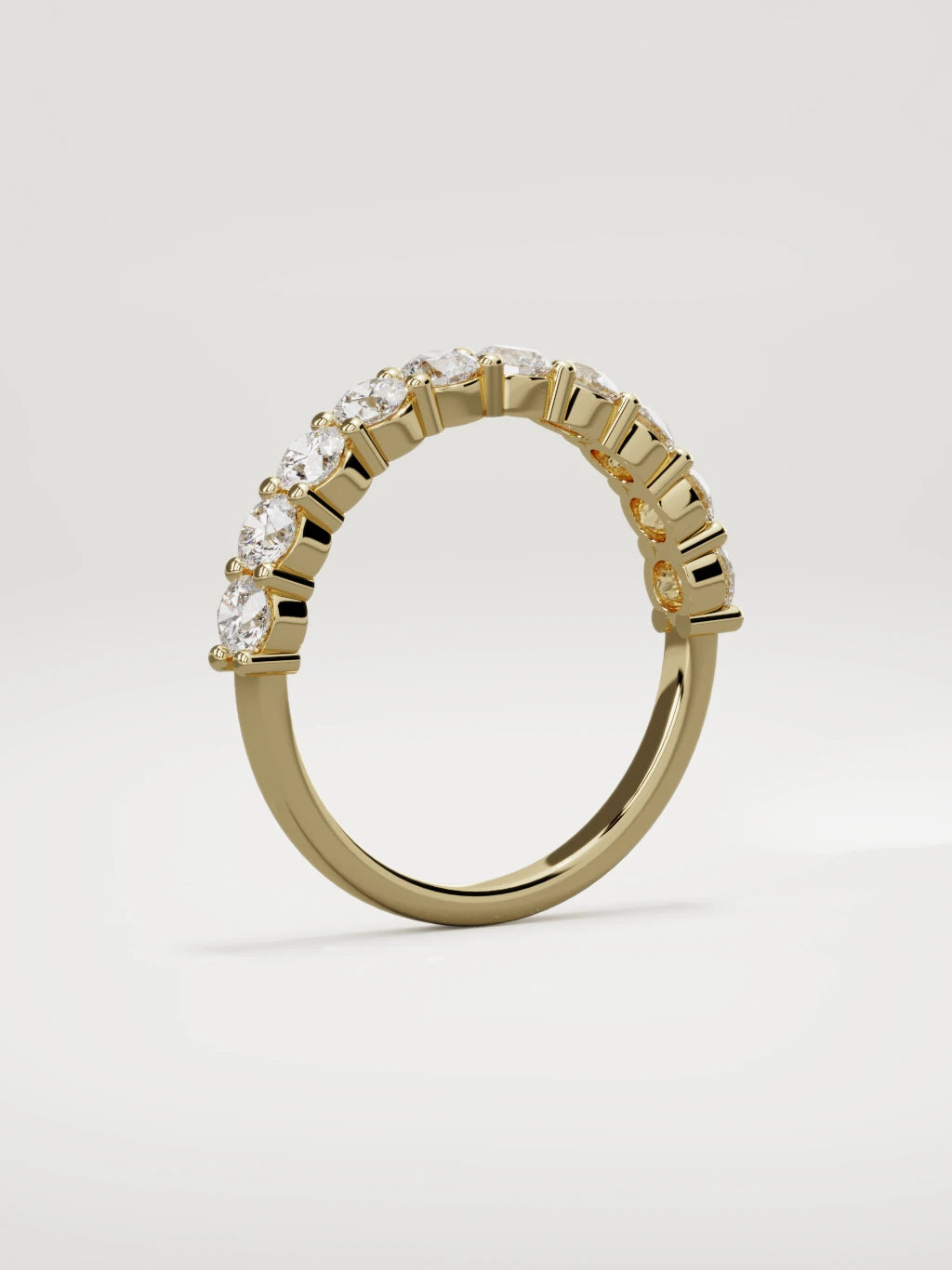 The Clara shared-prong half eternity band in 14K yellow gold, standing three-quarter view