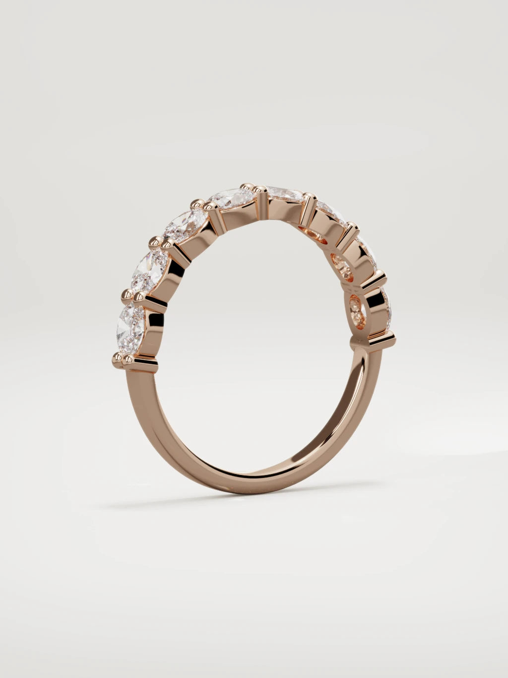 The Dama east-west oval half eternity band in 14K rose gold, standing three-quarter view