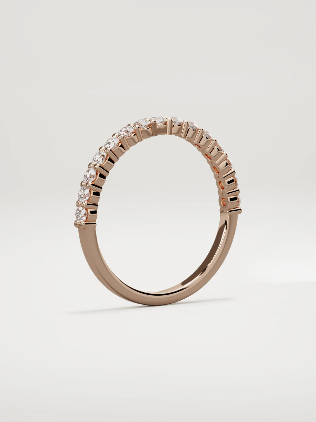 The Danza petite shared-prong half eternity band in 14K rose gold, standing three-quarter view