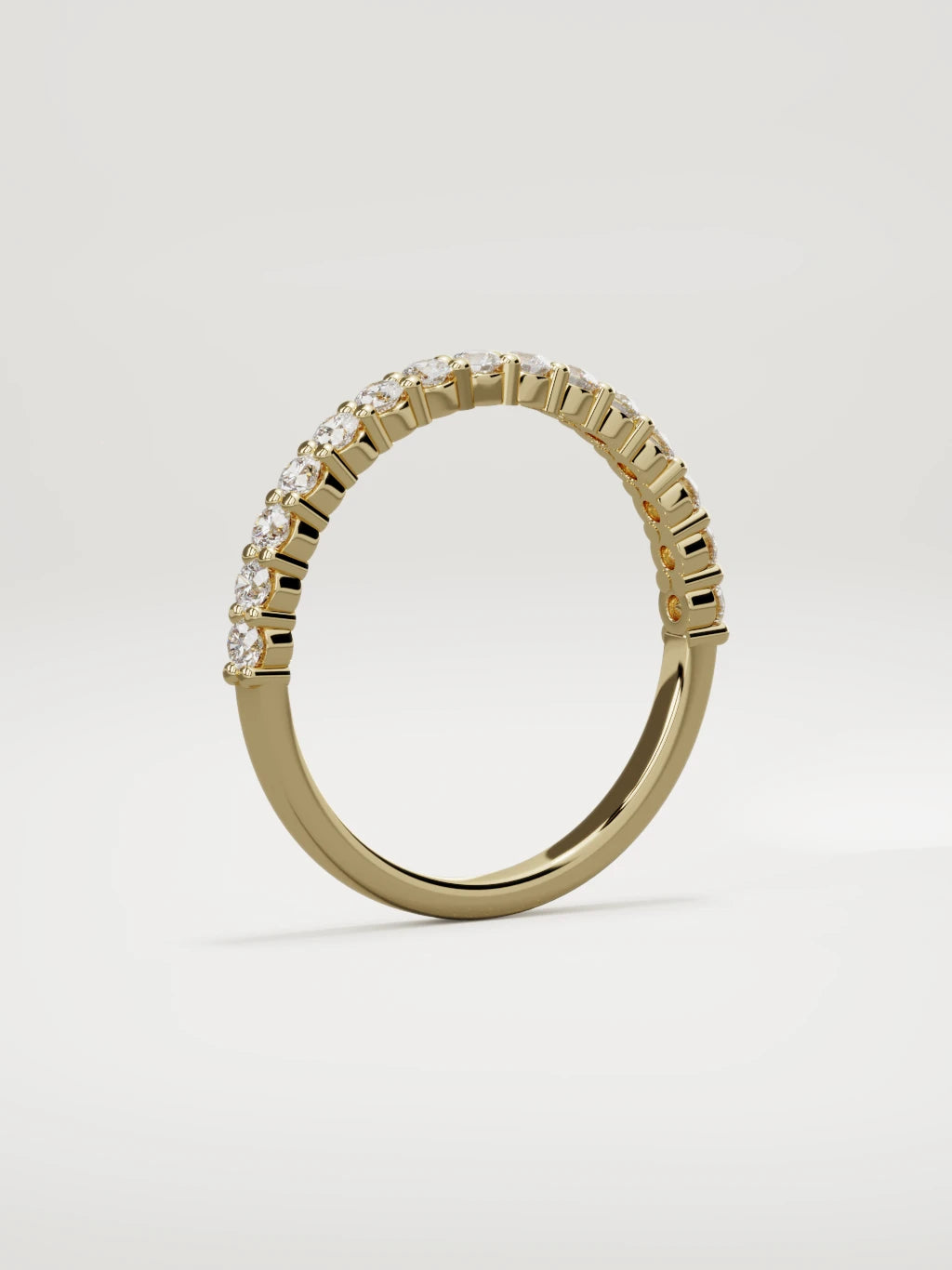 The Danza petite shared-prong half eternity band in 14K yellow gold, standing three-quarter view